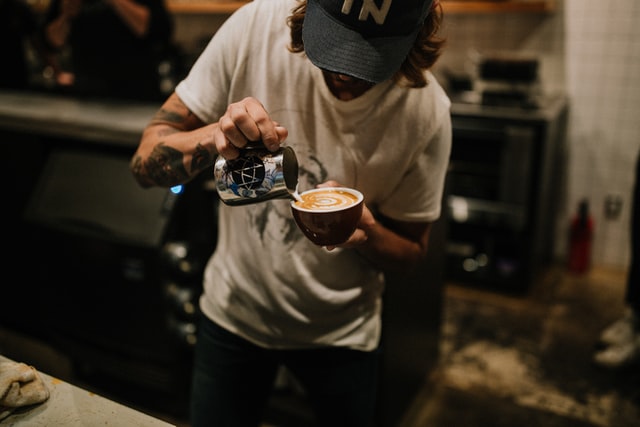 barista de café sirviendo un late y haciendo un dibujo con la espuma