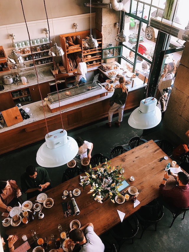 Vista de local de pastelerìa con el mostrador y una mesa con clientes.